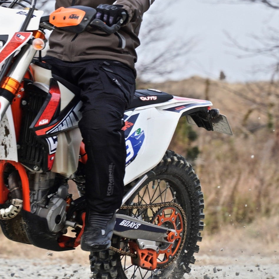 Person riding a dirt bike on a gravel path with a blurred natural background